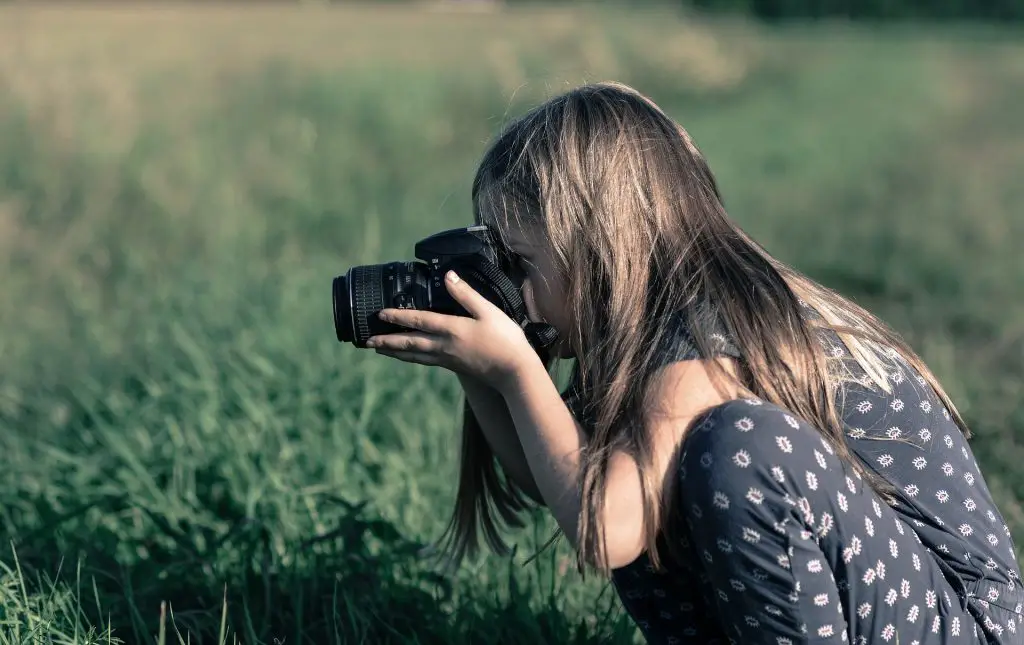 girl taking photo in field with best intermediate camera